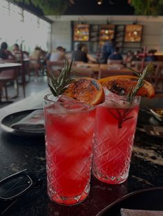 two glasses filled with drinks sitting on top of a table