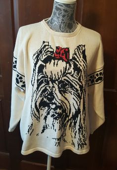 a white sweater with an image of a dog on the front and red bow at the back