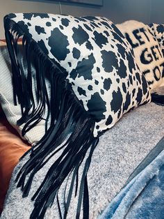 a black and white cow print pillow sitting on top of a couch next to a blanket