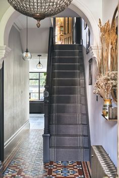 an entryway with stairs and tiled flooring in front of a chandelier