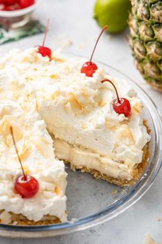 a piece of cake with white frosting and cherries on top sits on a plate