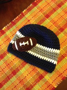 a crocheted hat with a football on it sitting on top of a table