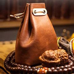 a brown leather purse sitting on top of a wooden table next to fruit and nuts