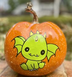 an orange pumpkin with a green dragon painted on it