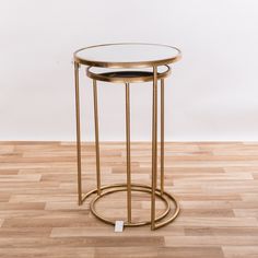 two round tables with gold metal bases on wooden flooring and white wall in the background