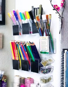 there are many pens, pencils, and markers on the wall next to each other