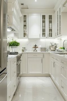 a white kitchen with stainless steel appliances and marble counter tops is pictured in this image