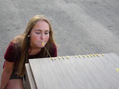 a young woman sitting on the ground eating something out of her mouth while looking down