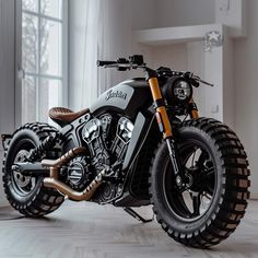 a black and white motorcycle parked in a room next to a window with large windows