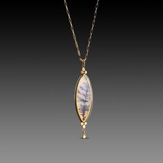 A very special dendritic agate evokes a mysterious and lovely scene in nature. The stone is wrapped in 22k gold, and accented with two 22k gold trios, and a tiny gold drop. This magical pendant is backed in sterling silver, and suspended from a 14k gold paperclip chain. Pendant measures approximately 1/2 inch x 1 3/4 inches. Matte finish. This piece is in stock and ready to ship.