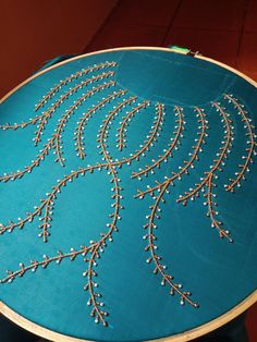 a table that has some kind of embroidery on it with beads in the shape of a peacock