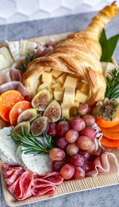 an assortment of meats and cheeses on a platter with fruit, bread