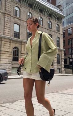 a woman is walking down the street with her handbag on her hip and wearing high heeled sandals