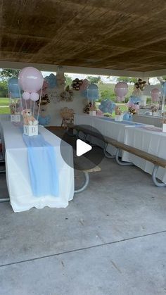 an outdoor party with balloons and table cloths on the tables under a covered area