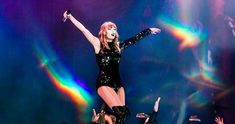 taylor swift performing on stage with her arms in the air and hands out to the crowd