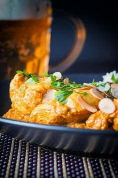 a close up of a plate of food on a table with a drink in the background