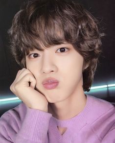 the young man is wearing a pink sweater and posing for a photo with his hand on his chin