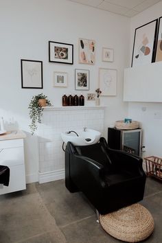 a black chair sitting in a room next to a white wall with pictures on it