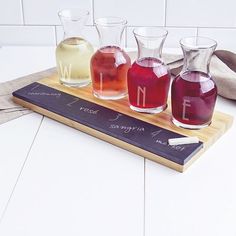 three different colored glasses sitting on top of a wooden tray