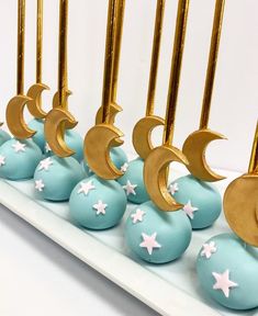 blue and gold cake pops with stars and crescents on them are lined up in rows