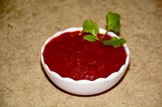 a small white bowl filled with red sauce and garnish