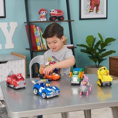 a young boy playing with toy cars on a table in his home office area,