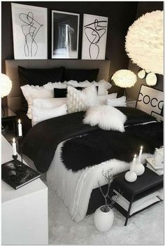 a black and white bedroom with pictures on the wall, candles in front of bed