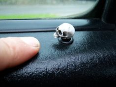 a small white skull sitting on top of a black car seat next to a window