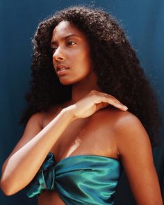 a woman in a green dress posing for the camera with her hand on her shoulder