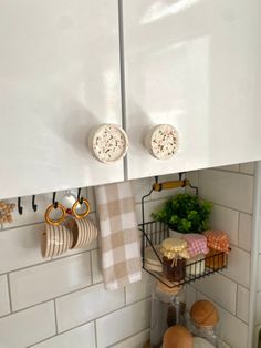 a kitchen with white cupboards and wooden cutting boards on the counter top, next to a wire rack filled with utensils