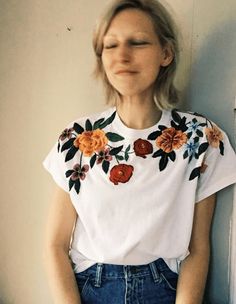 a woman sitting on the floor with her hands in her pockets and looking off to the side