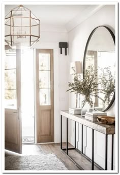 a hallway with a mirror, table and vase on the sideboard in front of it