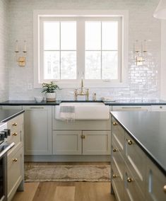 a kitchen with white cabinets and black counter tops, gold pulls on the sink, and brass knobs