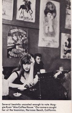 black and white photograph of people sitting at tables in a restaurant with posters on the wall