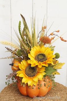 a pumpkin vase filled with sunflowers and other flowers