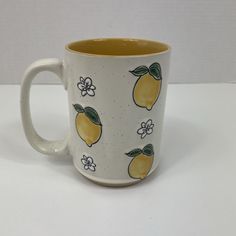 a yellow and white coffee cup with lemons on it