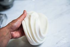 a hand holding a white object on top of a table