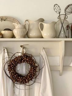 a wreath is hanging on a shelf with other dishes and vases in the background