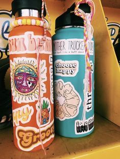 two colorful water bottles sitting on top of a shelf