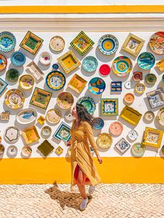 a woman walking past a wall covered in plates