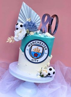 a cake decorated with soccer balls and flowers on a stand in front of a pink wall