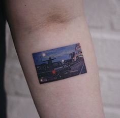 a person with a small tattoo on their arm that has a picture of a car in the background