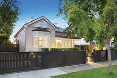 a white house with black fence and trees