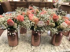 several vases filled with pink and white flowers on a counter top in front of a couch