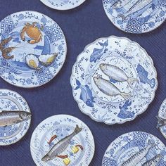 blue and white plates with fish painted on them are arranged in rows against a dark background