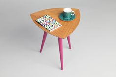 a small wooden table with a tea cup on it and a polka dot napkin underneath