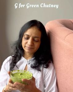 a woman sitting on a couch holding a bowl of guacamole in her hand