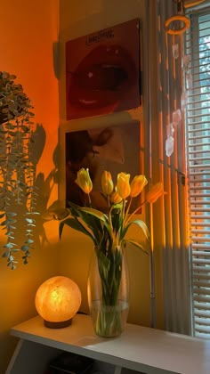 a vase filled with yellow flowers sitting on top of a white table next to a window