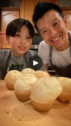 a father and son posing for a photo in front of baked goods on a cutting board