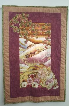 a quilted wall hanging on the side of a wall with trees and flowers in it